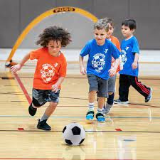 Young Kids Kicking Soccer Ball In Gym