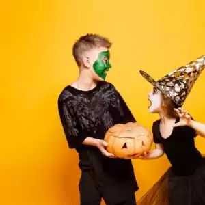 Kids In Halloween Costumes Playing With Pumpkin