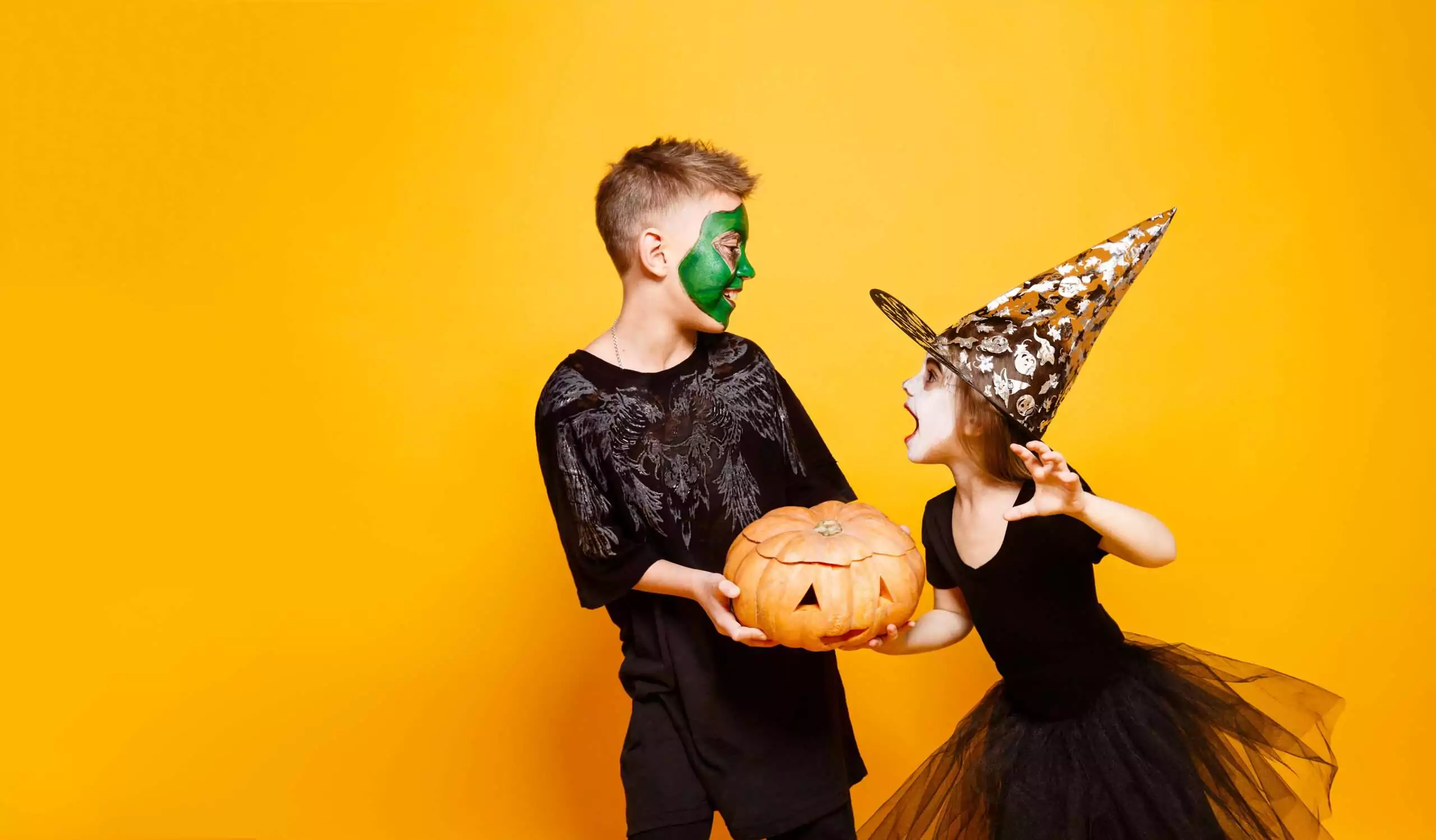 Kids In Halloween Costumes Playing With Pumpkin
